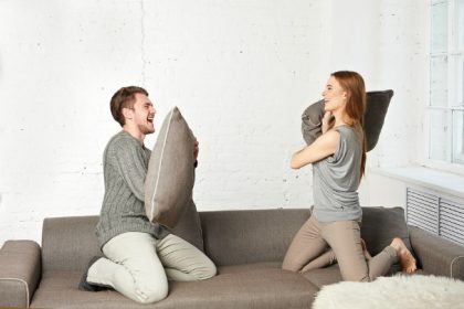 Happy Couple Fighting with Pillows on Coach